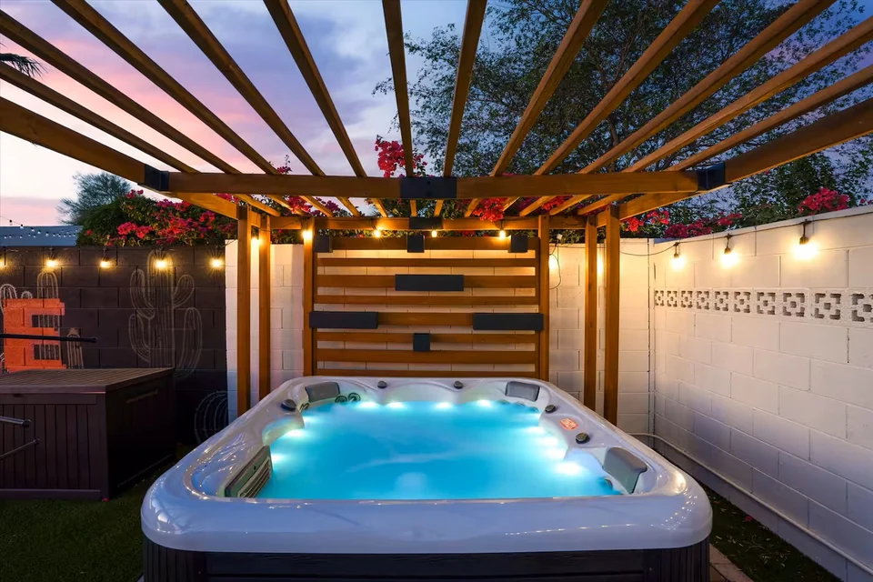 Private hot tub under a pergola with string lights at dusk