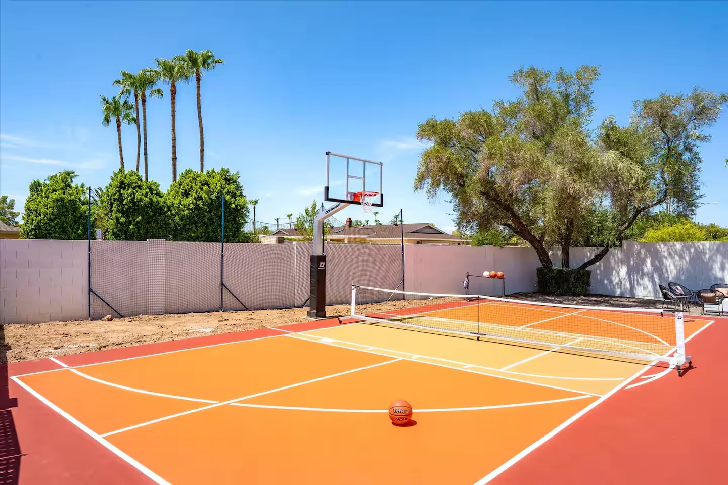 Private sport court with basketball hoop, pickleball net and palm trees
