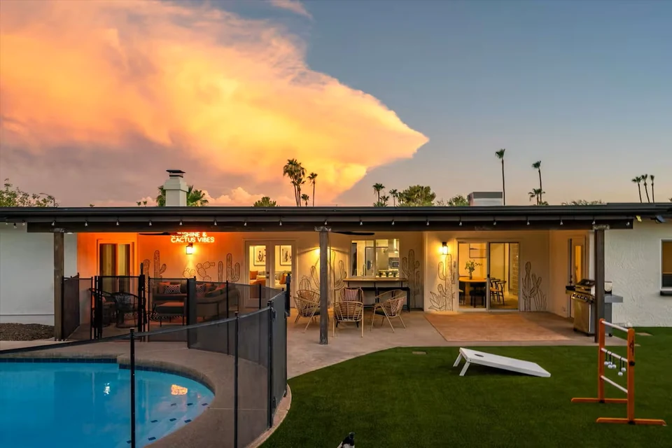 Covered patio with cactus murals and neon sign at dusk
