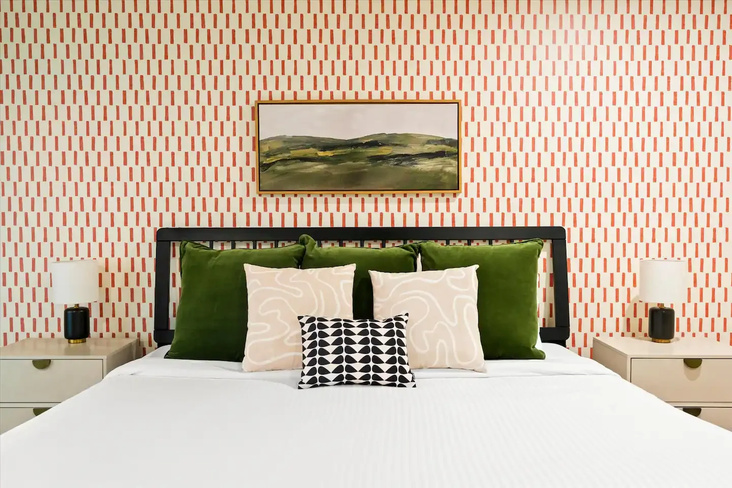 King bedroom with orange striped wallpaper, green velvet pillows and desert artwork